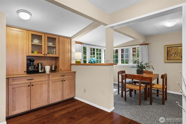 dining area featuring dark wood-type flooring, baseboards, and vaulted ceiling with beams