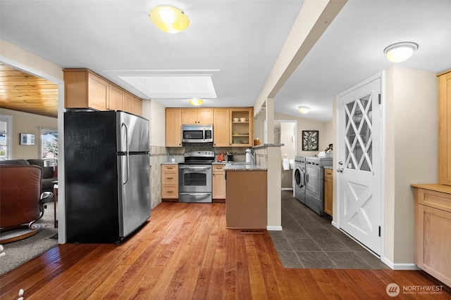 kitchen featuring washer and dryer, tasteful backsplash, appliances with stainless steel finishes, and wood finished floors
