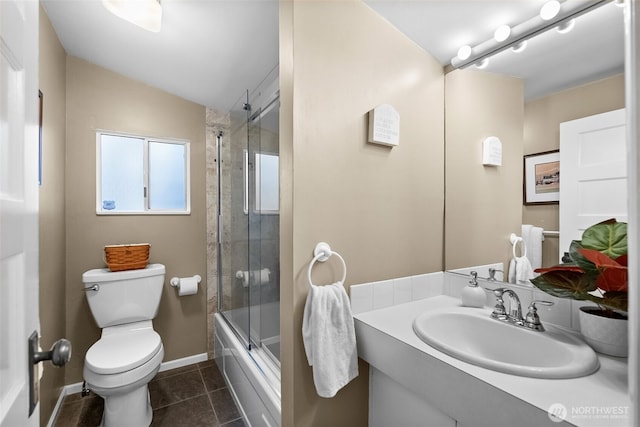bathroom featuring shower / bath combination with glass door, vanity, baseboards, tile patterned floors, and toilet