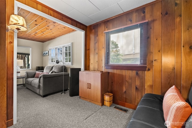 carpeted living room featuring wooden walls and visible vents