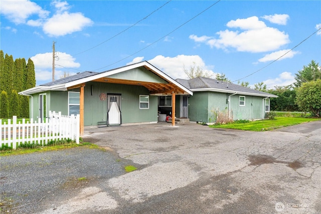 ranch-style house with a front lawn, fence, and aphalt driveway