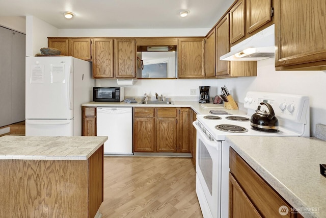 7806 Birch Bay Dr Unit 1107, Blaine, WA 98230 - kitchen with white appliances, brown cabinetry, light wood-type flooring, under cabinet range hood, and light countertops