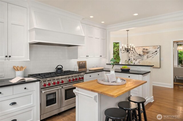 1919 Shenandoah Dr E, Seattle, WA 98112 - kitchen featuring range with two ovens, butcher block counters, custom exhaust hood, healthy amount of natural light, and ornamental molding