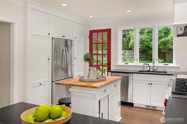 1919 Shenandoah Dr E, Seattle, WA 98112 - kitchen featuring appliances with stainless steel finishes, butcher block counters, a sink, white cabinets, and crown molding