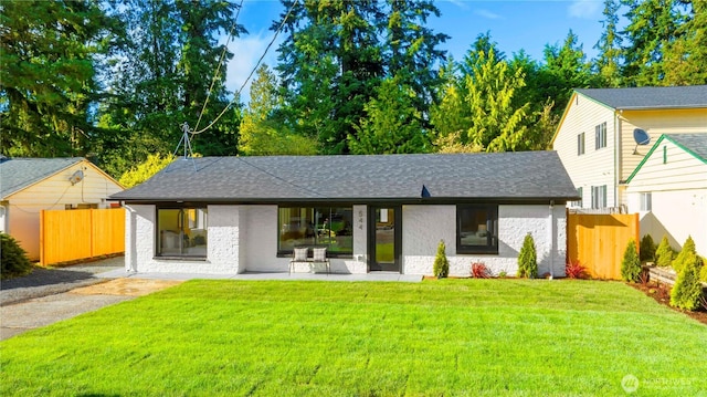 view of front of property with a shingled roof, a patio area, fence, and a front lawn