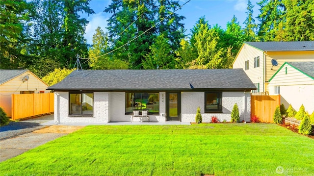 view of front of house featuring a front lawn, fence, and roof with shingles