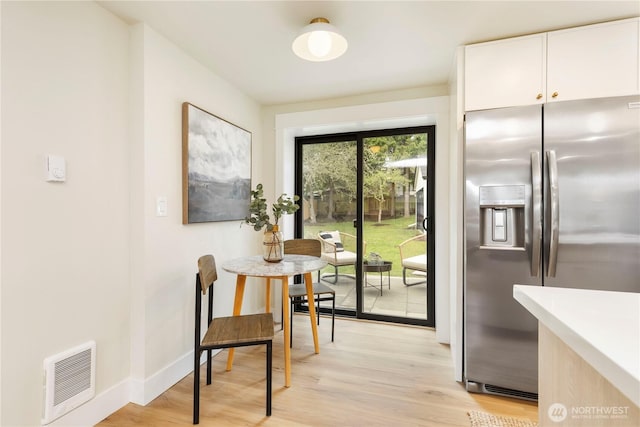 dining space featuring light wood finished floors, baseboards, and visible vents