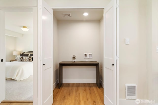 corridor featuring light wood-style flooring, baseboards, and visible vents