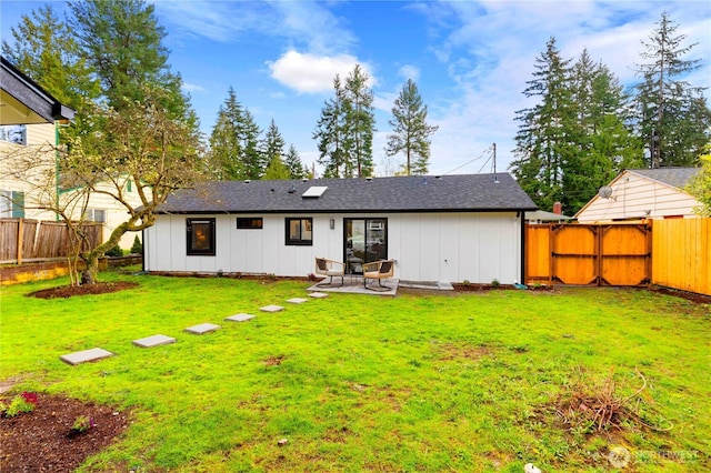 rear view of property featuring a patio, board and batten siding, a fenced backyard, and a yard