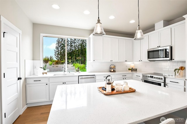 kitchen featuring backsplash, white cabinetry, appliances with stainless steel finishes, and a sink
