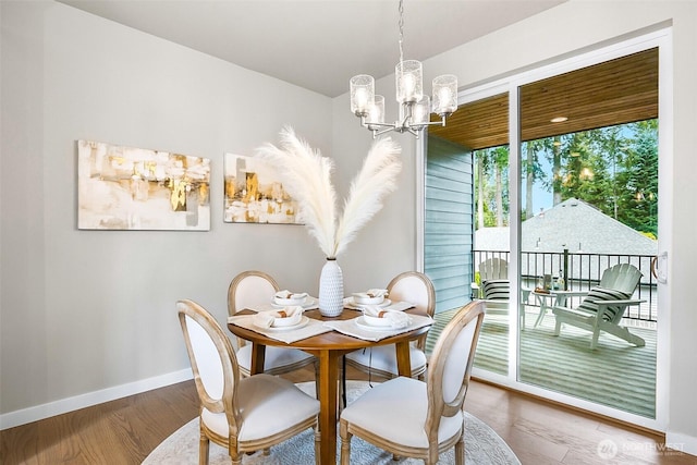 dining area with baseboards, an inviting chandelier, and wood finished floors
