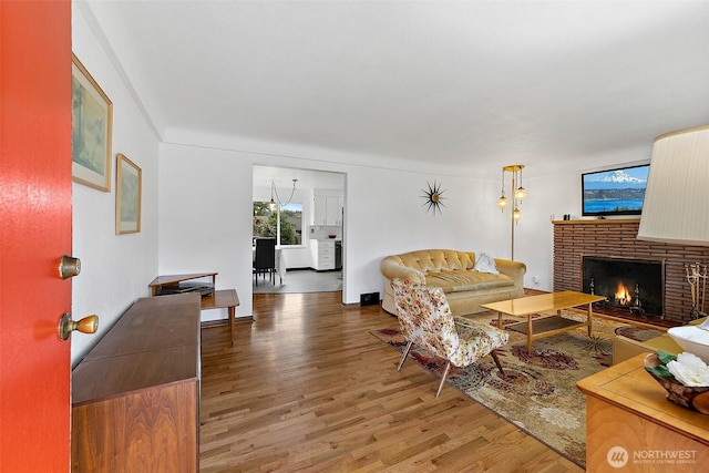 living room featuring a brick fireplace and wood finished floors