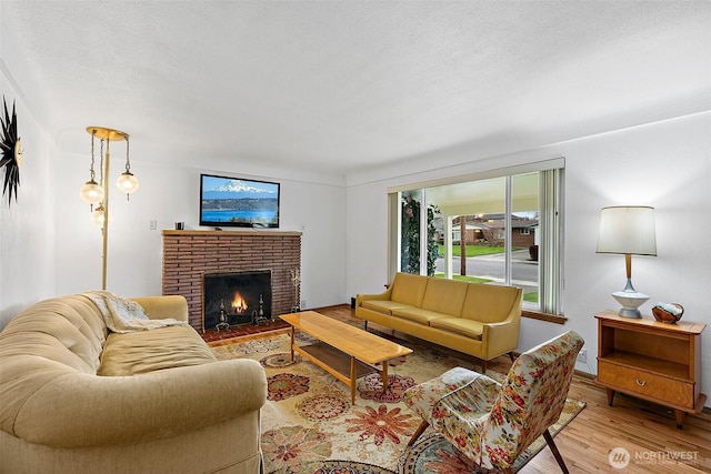 living area featuring a textured ceiling, wood finished floors, and a fireplace