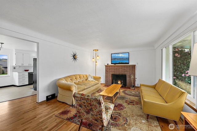 living room featuring light wood-style flooring, a fireplace, and baseboards