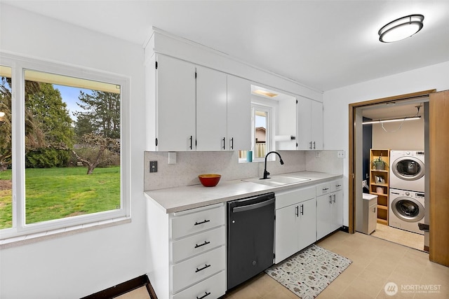 kitchen with light countertops, dishwashing machine, stacked washer / drying machine, and a sink