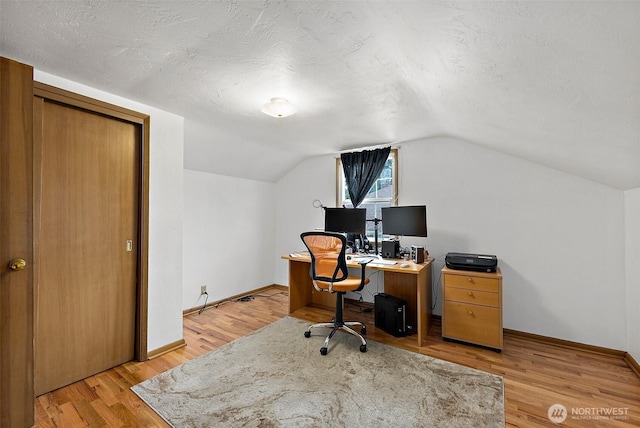 office space with baseboards, light wood-type flooring, and a textured ceiling