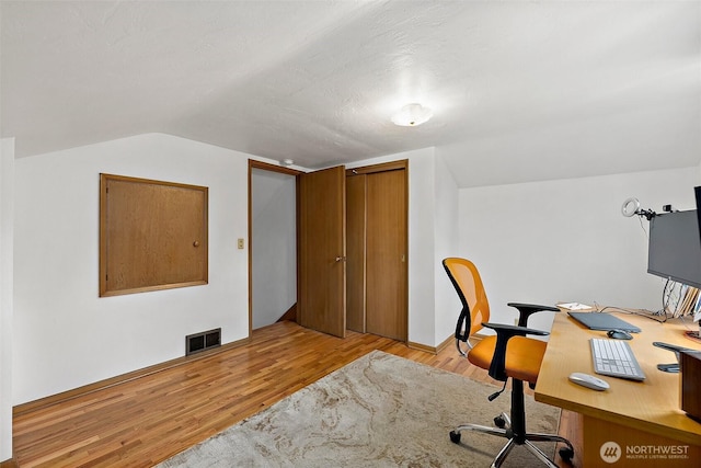 office featuring visible vents, vaulted ceiling, and wood finished floors