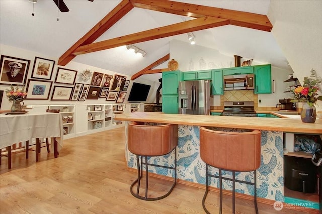 kitchen with lofted ceiling with beams, light wood-type flooring, appliances with stainless steel finishes, a kitchen bar, and green cabinets