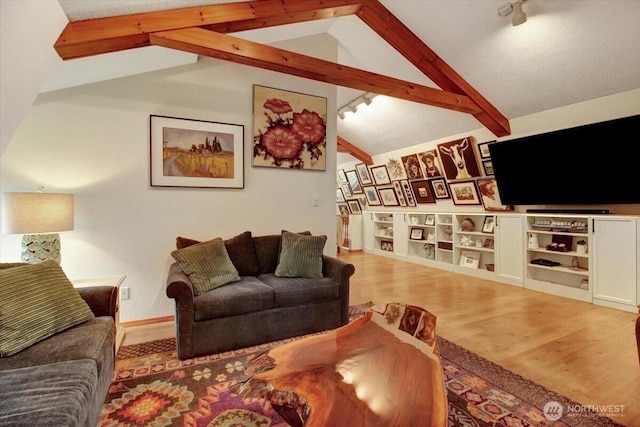 living area with track lighting, wood finished floors, baseboards, and vaulted ceiling with beams