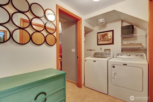 washroom with laundry area, light tile patterned floors, baseboards, and washing machine and dryer