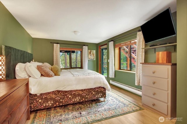 bedroom with baseboard heating and wood finished floors