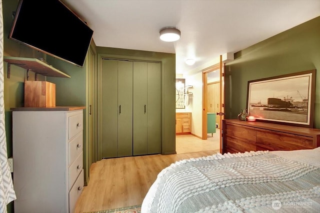 bedroom with ensuite bath, light wood-style floors, and a closet