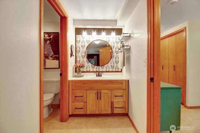 bathroom with tile patterned flooring, vanity, baseboards, and toilet