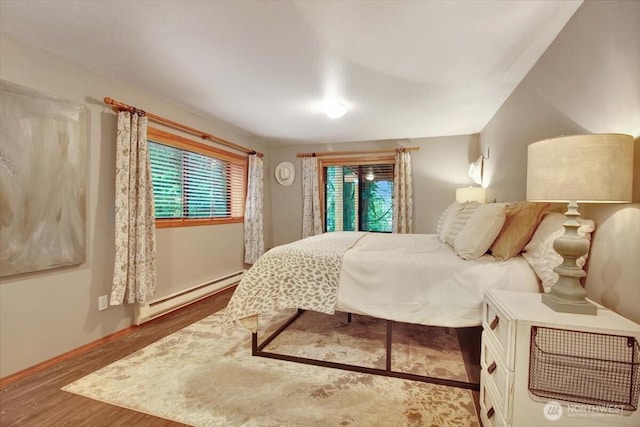 bedroom featuring a baseboard radiator, wood finished floors, and baseboards
