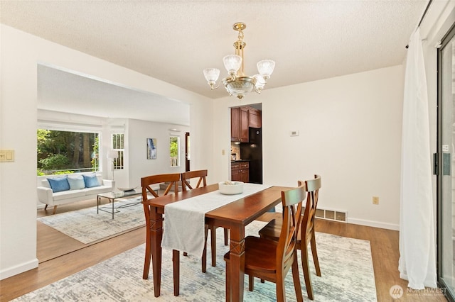 20817 29th Ave SE, Bothell, WA 98021 - dining area featuring a chandelier, light wood finished floors, a textured ceiling, and baseboards