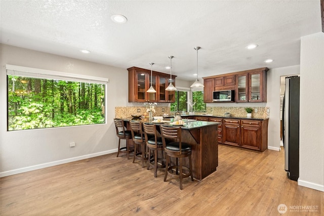 20817 29th Ave SE, Bothell, WA 98021 - kitchen featuring appliances with stainless steel finishes, a peninsula, tasteful backsplash, a kitchen bar, and light wood finished floors