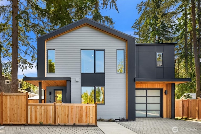 contemporary home with driveway, fence private yard, and a garage