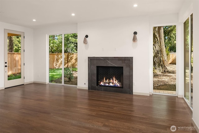 unfurnished living room with baseboards, recessed lighting, wood finished floors, and a fireplace
