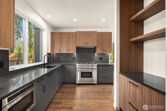 kitchen with tasteful backsplash, open shelves, appliances with stainless steel finishes, dark wood-style flooring, and a sink