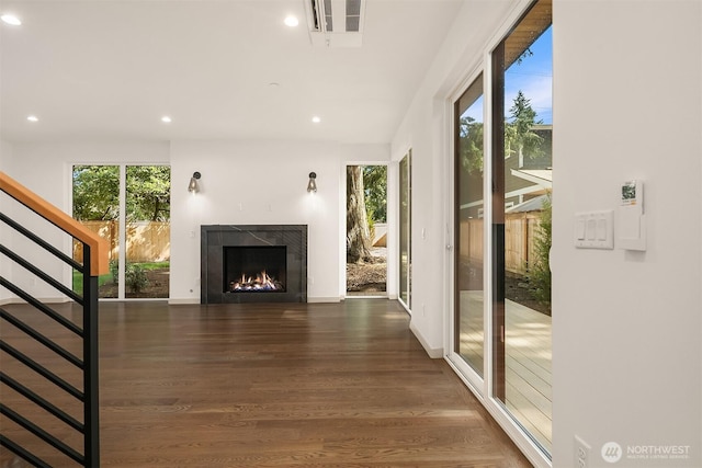 doorway to outside featuring recessed lighting, wood finished floors, stairs, and a lit fireplace