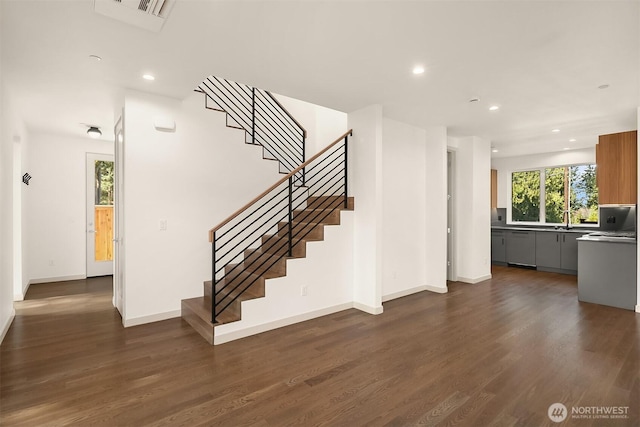 stairs with wood finished floors, recessed lighting, visible vents, and baseboards