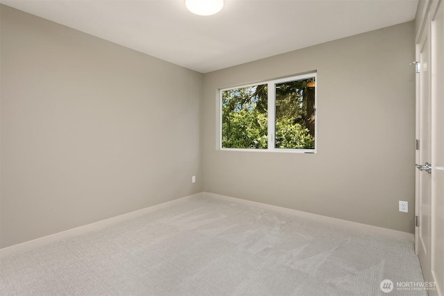 spare room with light colored carpet and baseboards