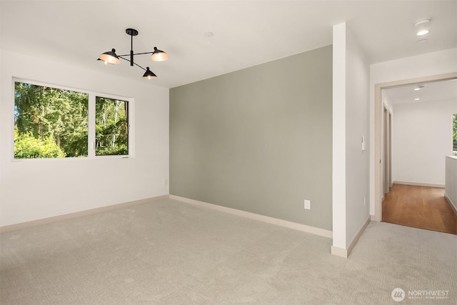 empty room with recessed lighting, a notable chandelier, light colored carpet, and baseboards
