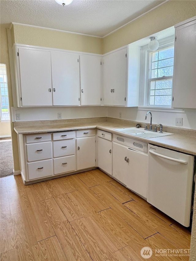 kitchen featuring a wealth of natural light, white cabinetry, dishwasher, light countertops, and a sink