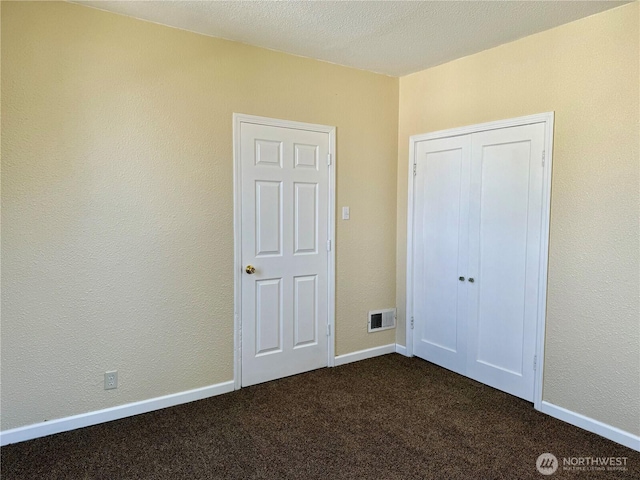 unfurnished bedroom with visible vents, a closet, and dark carpet