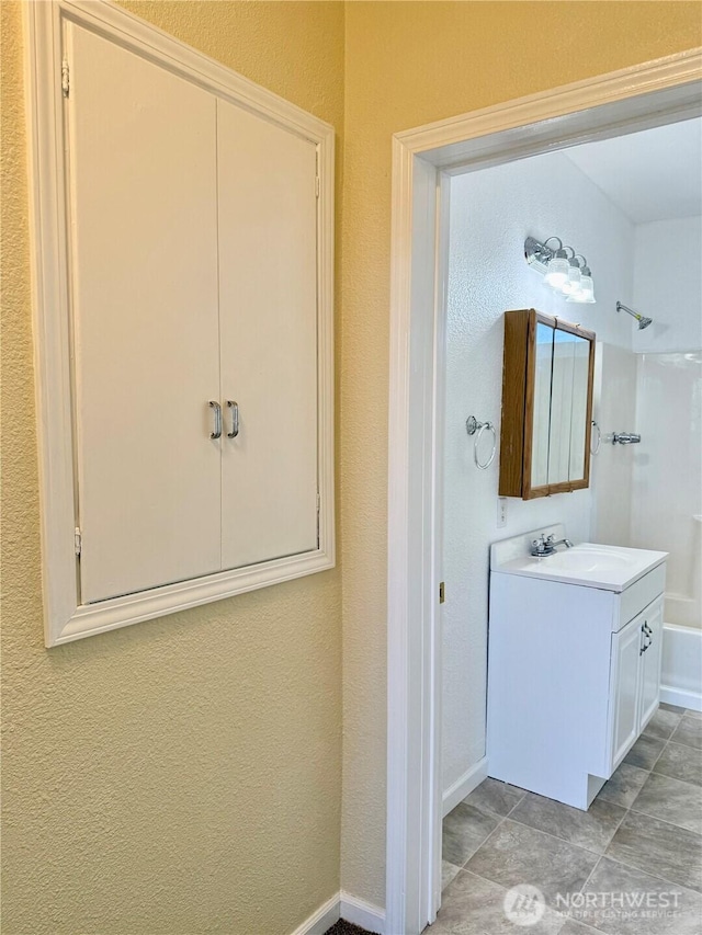 bathroom with baseboards, vanity, and shower / washtub combination