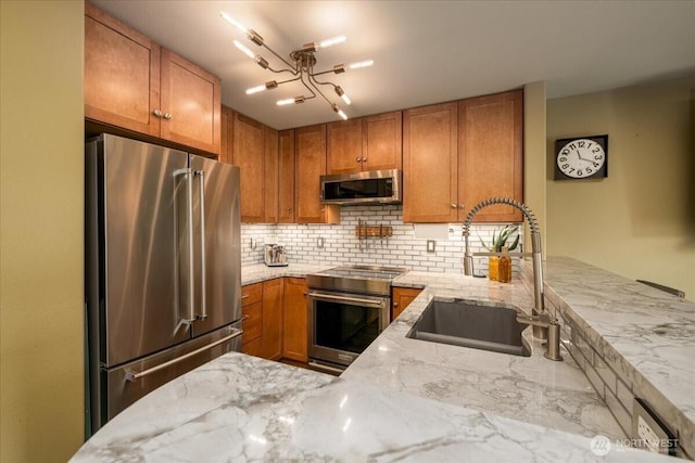 3435 California Ave SW Unit 405, Seattle, WA 98116 - kitchen featuring high quality appliances, light stone countertops, brown cabinets, decorative backsplash, and a sink