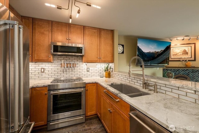 3435 California Ave SW Unit 405, Seattle, WA 98116 - kitchen with light stone countertops, brown cabinetry, a sink, stainless steel appliances, and backsplash