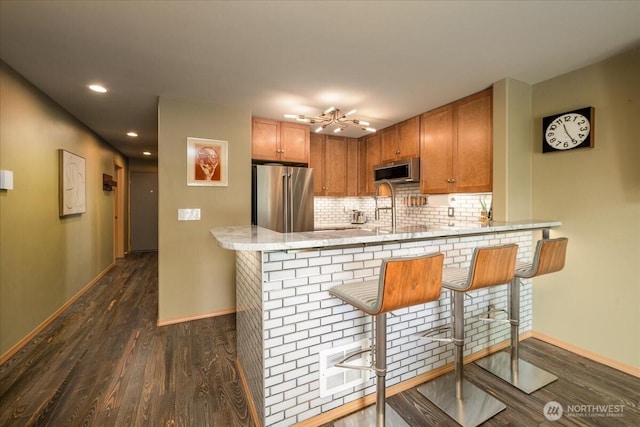 3435 California Ave SW Unit 405, Seattle, WA 98116 - kitchen featuring visible vents, baseboards, a peninsula, dark wood-style floors, and stainless steel appliances