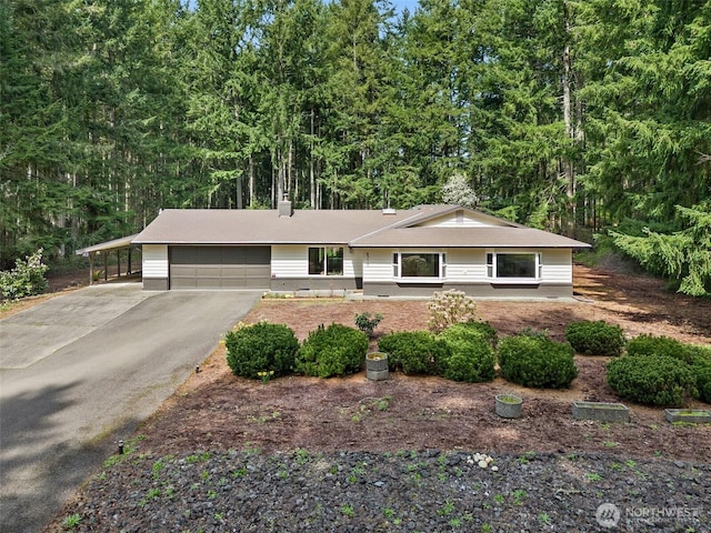 8710 Homestead Ave NE, Olympia, WA 98516 - ranch-style house with a carport, a forest view, an attached garage, and aphalt driveway