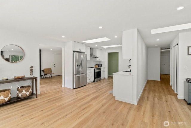 8710 Homestead Ave NE, Olympia, WA 98516 - kitchen featuring white cabinets, wall chimney exhaust hood, a skylight, stainless steel appliances, and a sink