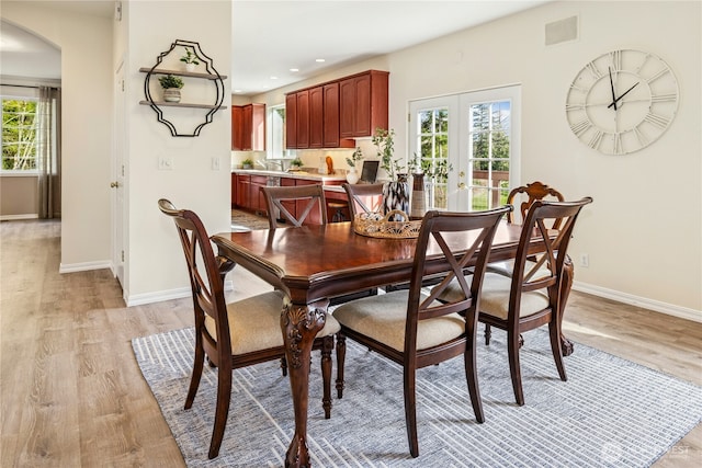 dining room with visible vents, a wealth of natural light, light wood-type flooring, and arched walkways