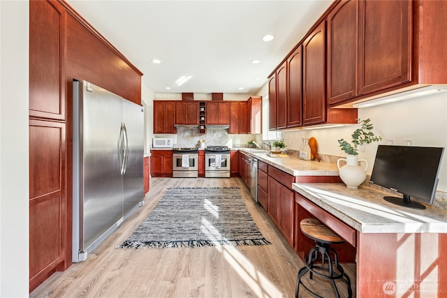 kitchen with tasteful backsplash, light countertops, recessed lighting, stainless steel appliances, and light wood-style flooring