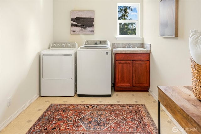 laundry area with baseboards, a sink, cabinet space, washing machine and clothes dryer, and light floors