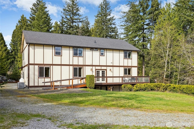 back of house featuring board and batten siding, a shingled roof, a deck, and a yard