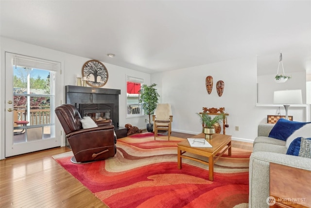 living area with a tile fireplace, wood finished floors, and baseboards